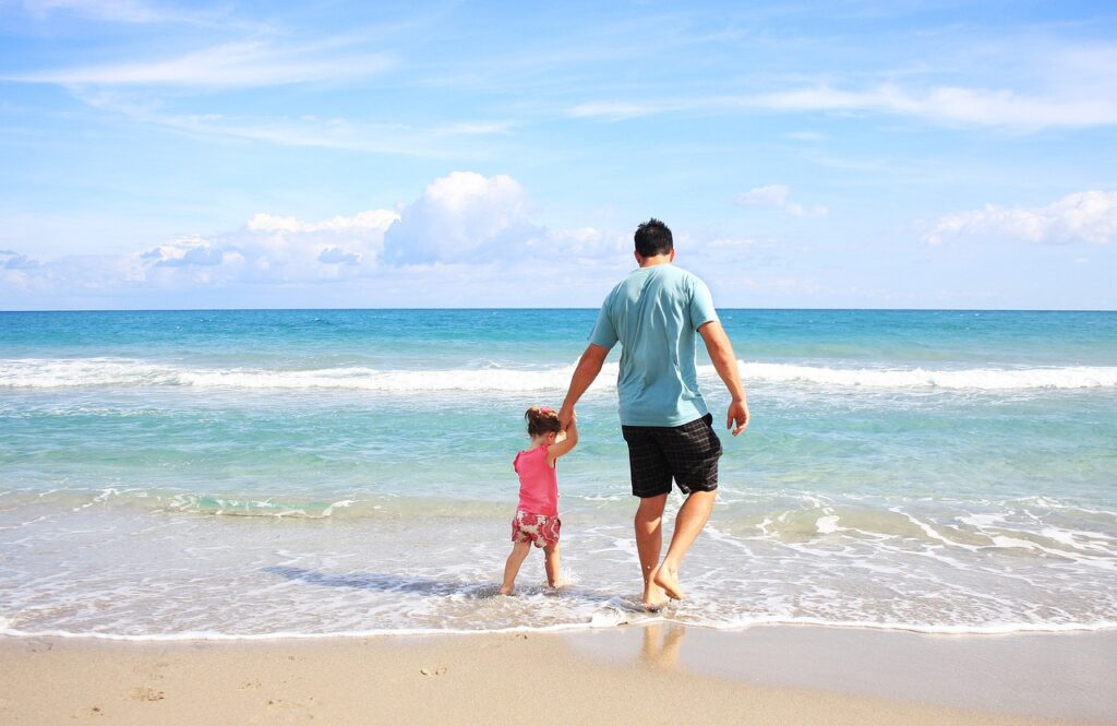 Vater und Tochter spazieren am Strand Strandurlaub zum kleinen Preis So wird Ihr Ostseeurlaub erschwinglich