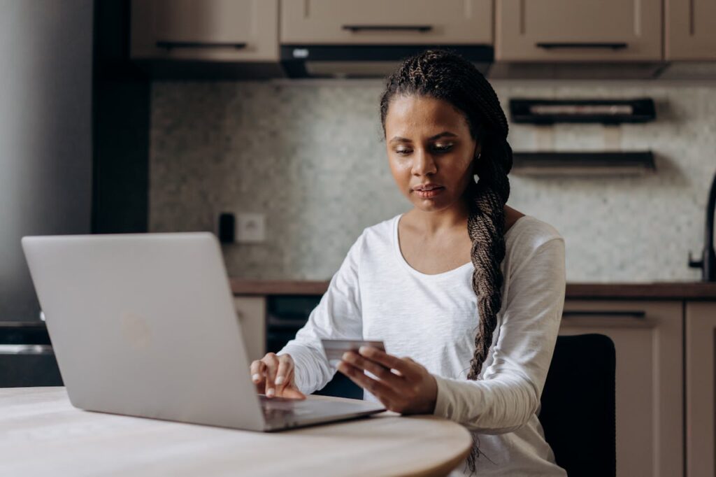 afroamerikanische Frau blickt auf Kreditkarte Laptop Die Geschichte der Kreditkarte Wie alles begann